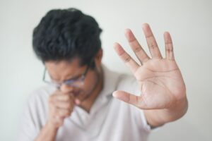 Can gum disease make you sick? Person holding hand up and other hand holding mouth in pain, Periodontal Health Center for gum disease treatment