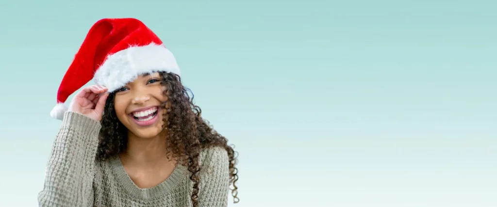 woman in a santa hat smiles and talks about stocking stuffer ideas